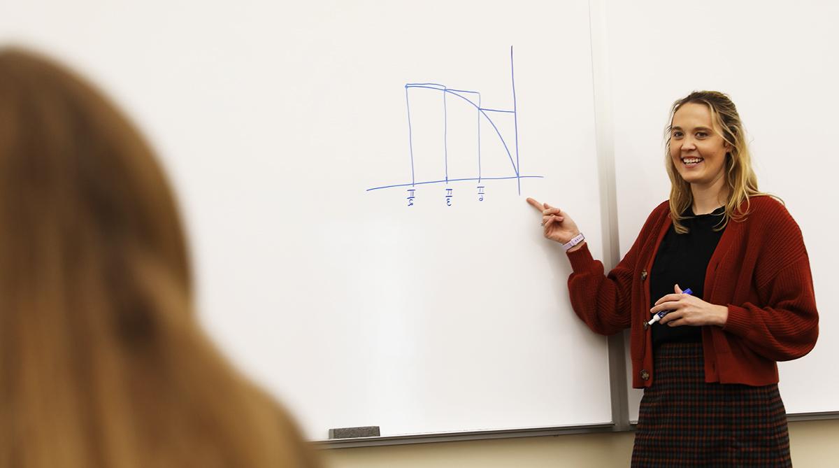 professor pointing at equation on whiteboard